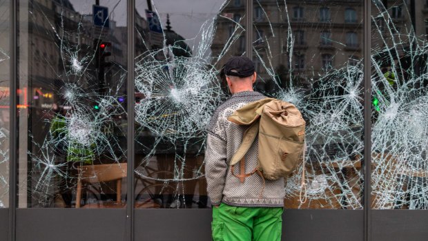 A person looks at shattered windows on a Starbucks Corp. cafe during the yellow vests (Gilets jaunes) protests in Paris on Saturday.