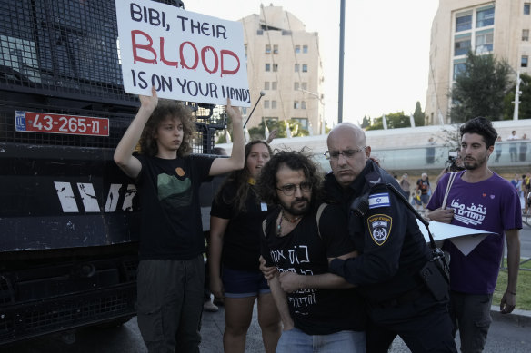 An Israeli police officer removes a demonstrator blocking a road during a protest calling for a deal to release the remaining Gaza hostages.