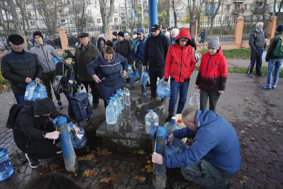 People fill containers with water from public water pumps in Kyiv.