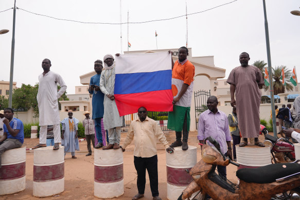 Supporters of mutinous soldiers hold a Russian flag as they demonstrate in Niamey, Niger.