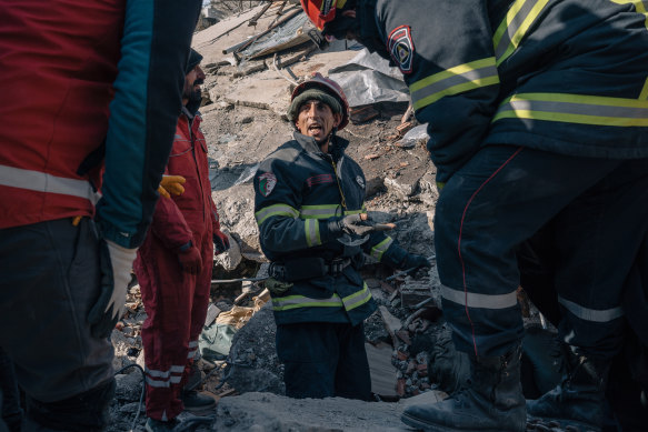 A member of an Algerian rescue team communicates with a Turkish team through interpreters as they work to retrieve a body from the earthquake rubble in Adiyaman, Turkey.