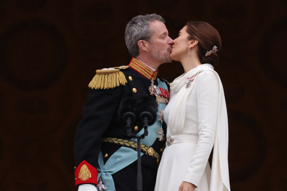 The new king and queen kiss on the palace balcony.