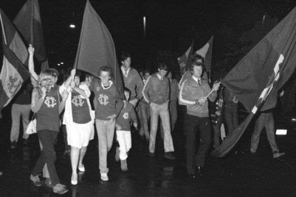 Lions’ old warrior Kevin Murray carrying the club banner, led players up Brunswick Street along the tramline to the ground.