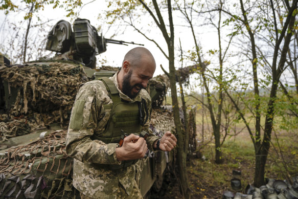 A Ukrainian soldier speaks to his brothers in arms while his unit waits for order to fire in Bakhmut, Ukraine, Sunday.