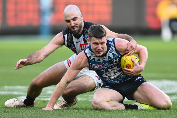 Sam Walsh of the Blues is tackled by Steele Sidebottom of the Magpies.