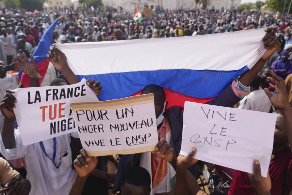 Nigeriens holding a Russian flag and placards participate in a march called by supporters of coup leader General Abdourahmane Tchiani in Niamey, Niger.