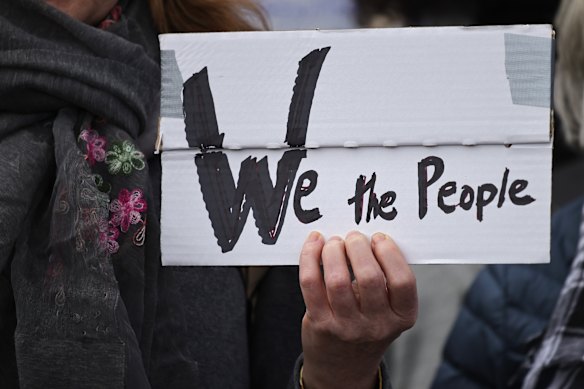  A demonstrator holds a banner reading “We the people” as people protest outside the US embassy against US President Donald Trump and  adviser Elon Musk on April 5  in Berlin, Germany. 