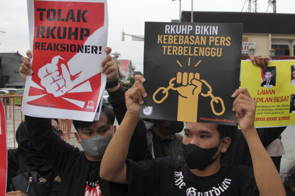 Activists hold up posters during a rally against Indonesia’s new criminal law.