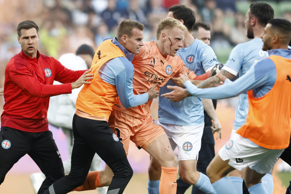 A bleeding Tom Glover of Melbourne City is escorted from the pitch by teammates on December 17, 2022