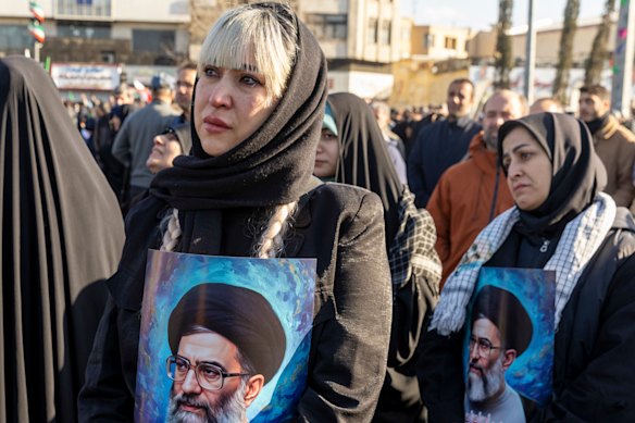 Women hold posters as thousands of people gather in Enghelab Square, Tehran, after Iranian state media confirmed the death of Ayatollah Ali Khamenei.