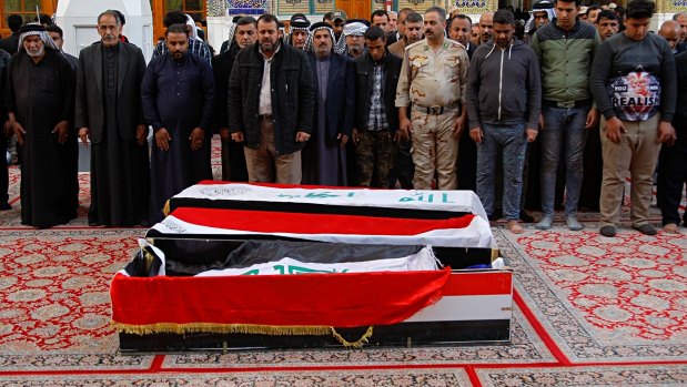 Mourners pray over the flag-draped coffins of three bombing victims in Najaf, on Monday.