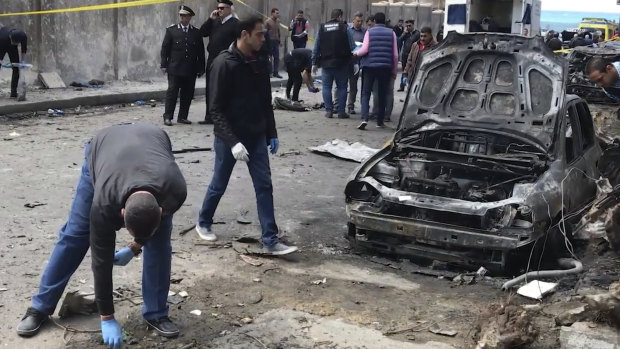 Security members search after a bomb placed under a nearby car exploded on Saturday in Alexandria, Egypt.