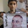Amro el Halabio, 7, holds a picture of his father, Mohammed, who was the Gaza director of the international charity World Vision, now found guilty of diverting sums to Hamas that exceed its total budget,