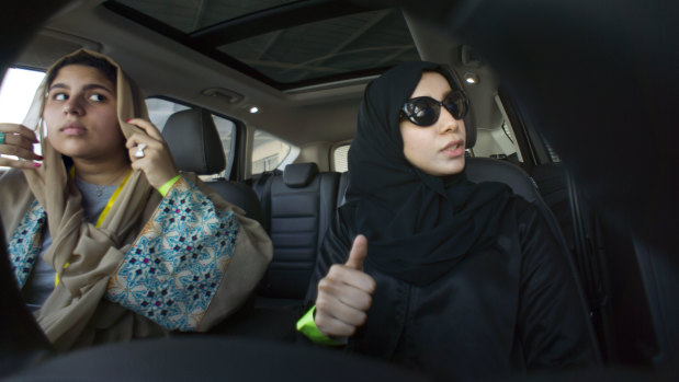 Fatima Salem, right, giggles as Sara Ghouth adjusts her veil, during training sponsored by Ford Motor, in Jiddah, Saudi Arabia.