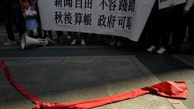 Protesters carry a banner with Chinese reads "Do not trample on press freedom" next to a red ribbon symbolising the bottom line of the Chinese Communist Party during a protest in Hong Kong.