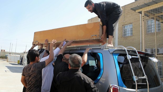Family members of slain activist Soad al-Ali load her coffin onto a vehicle before burial, in Basra, Iraq, on September 26.