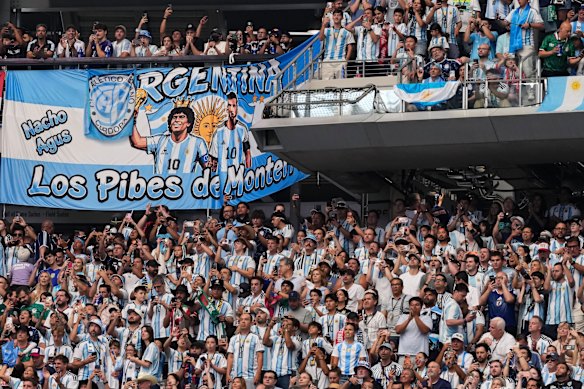 Fans of Argentina hold a flag with images of Lionel Messi and Diego Maradona.