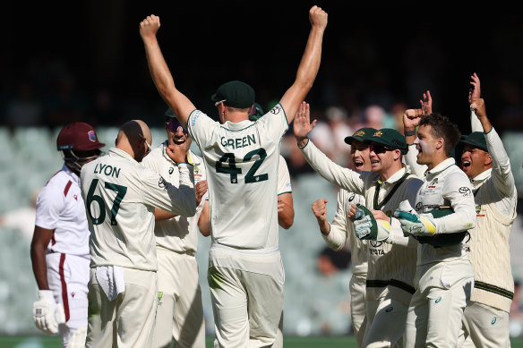 Nathan Lyon is mobbed by teammates after taking a wicket in Adelaide.