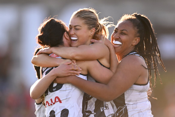 Ashleigh Brazill, Sarah Rowe and Sabrina Frederick of the Magpies celebrate a goal.