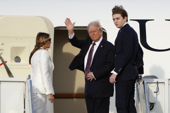President-elect Donald Trump, standing with Melania and Barron Trump, waves as they board an Air Force Special Mission aircraft at Palm Beach International Airport.