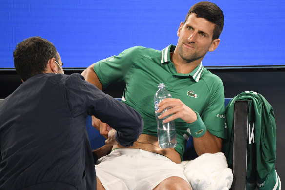 Novak Djokovic receives treatment during his third-round match against Taylor Fritz on Friday night.