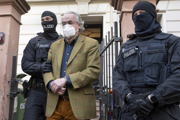 Masked police officers lead Heinrich XIII Prince Reuss, centre, to a police vehicle during a raid against coup plotters in Germany last week.