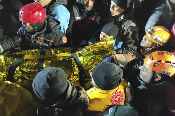 Rescue workers and medics carry a young woman rescued from the debris of a collapsed building in Sanliurfa, southern Turkey, on Monday.