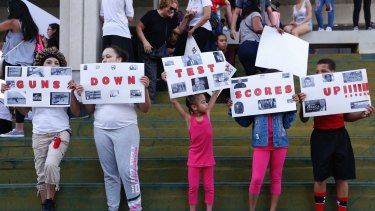 A group of people hold signs that read 'Guns Down Test Scores UP' during a protest against guns outside a federal courthouse in Florida. 