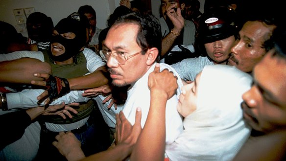 September 1998: Anwar Ibrahim's wife Wan Azizah Wan Ismail holds on to him as he is arrested at home by masked officers.