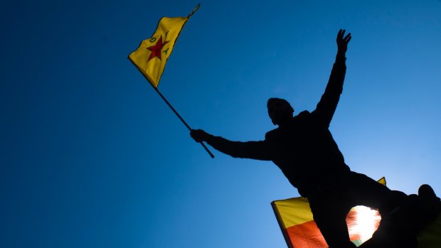 A man waves a flag with Kurdish symbols as he attends a demonstration of some thousand protesters against the Turkish offensive targeting Kurds in  northern Syria, in Berlin last week.