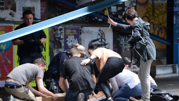 Bystanders and emergency workers attend to an injured person on Bourke Street a year ago.