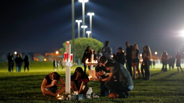 People pray around one of 17 crosses, after a candlelight vigil for the victims of the shooting at Marjory Stoneman Douglas High School, in Parkland, Florida.