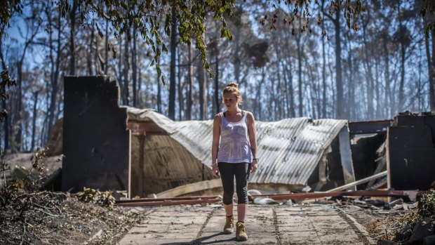 Juvette Jory looks at the rubble of her family home in Tathra