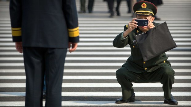 A military officer takes a smartphone photo of a fellow officer before a plenary session of the Chinese People's Political Consultative Conference.