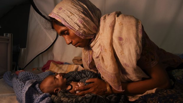 Laila Begum holds the hand of her malnourished, 40-day old son, Mohammed Ifran, as he receives treatment at the Red Cross Field Hospital in Kutupalong refugee camp. 
