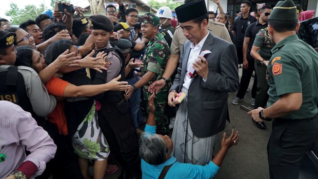 A woman cries at the feet of president Joko Widodo when complaining that her home has been destroyed in a land dispute.