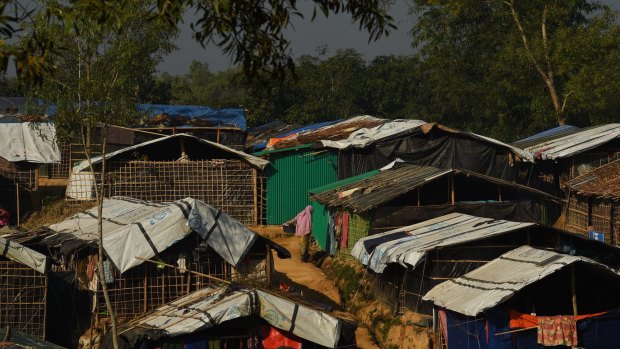 A woman holds a bucket of clothes as she stands among the shelters in Kutupalong refugee camp in Bangladesh.