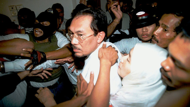 September 1998: Anwar Ibrahim's wife Wan Azizah Wan Ismail holds on to him as he is arrested at home by masked officers.