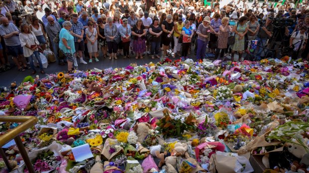 People remember the Bourke Street victims in front of the thousands of tributes left at the GPO building.