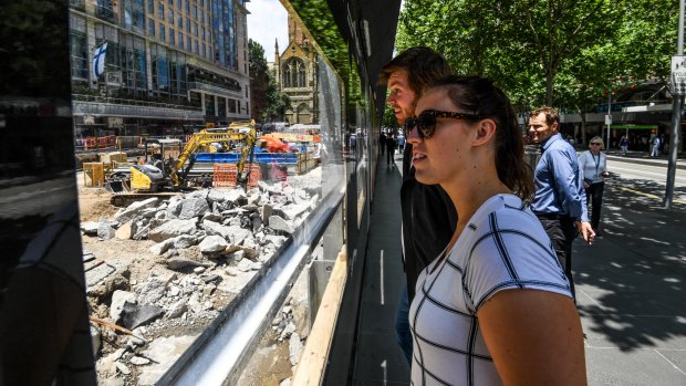 Passers-by watch as the City Square site is excavated to make way for  the underground Town Hall Station. 