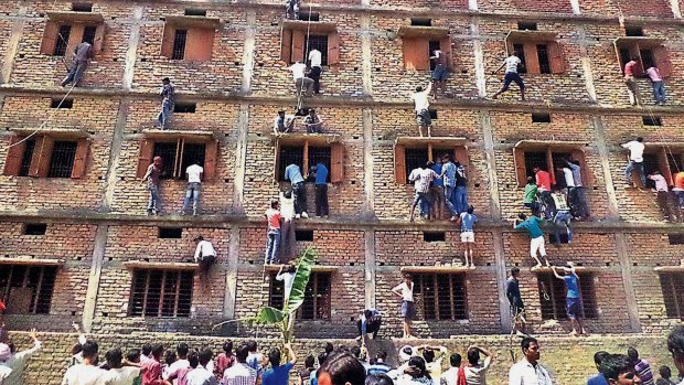 Indians climb the wall of a building to help students cheat, including their own children, appearing in an exam in 2015.