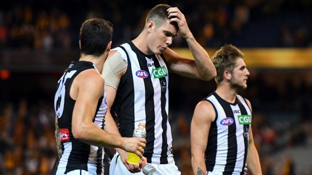 Rough day: Mason Cox (centre) and Magpies teammates after losing to the Hawks on Saturday. 
