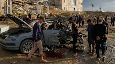 Palestinians looks at a destroyed car following an Israeli strike in Gaza City.