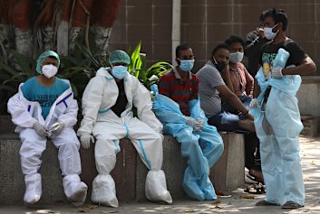 Health workers take rest in between cremating COVID 19 victims in New Delhi, India, Monday, April 19, 2021. New Delhi has imposed a weeklong lockdown to prevent the collapse of the Indian capital’s health system amid an explosive surge in coronavirus cases.
