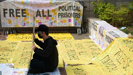 A supporter of pro-democracy activists holds a sign outside West Kowloon Magistrates’ Courts where others queue up for a court hearing over charges  of subversion on Monday.