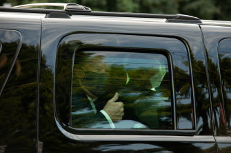 US President Donald Trump wears a face mask and gives supporters a thumbs up during a drive-by with secret service agents outside the hospital. 