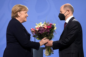 New German Chancellor Olaf Scholz hands flowers to his predecessor Angela Merkel during a handover ceremony in the chancellery in Berlin on Wednesday.