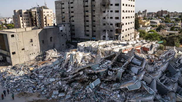People walk past view rubble of the al-Jalaa building destroyed in a previous air strike following a ceasefire reached after an 11-day war between Gaza’s Hamas rulers and Israel, in Gaza City.