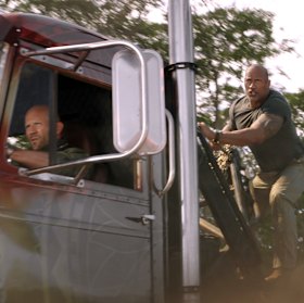 Jason Statham as Deckard Shaw (driving) and Dwayne Johnson as Luke Hobbs in the latest installment of Fast & Furious.
