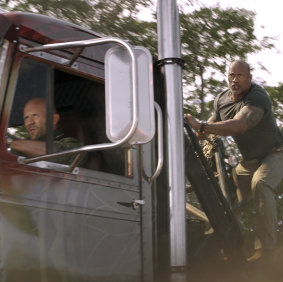 Jason Statham as Deckard Shaw (driving) and Dwayne Johnson as Luke Hobbs in the latest installment of Fast & Furious.
